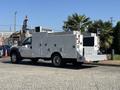 A 2011 Ford F-550 utility truck with a white body featuring tool compartments and a flatbed at the rear