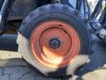 A close-up view of a tire from a 2015 Bobcat 5600 featuring a rugged tread pattern and an orange wheel rim with six visible bolts