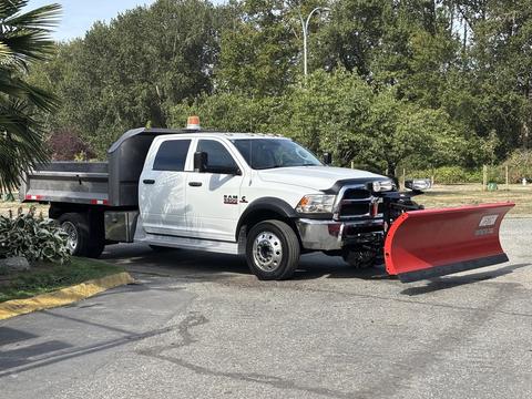 A 2013 RAM 5500 truck with a snow plow attached in front and a flatbed in the back