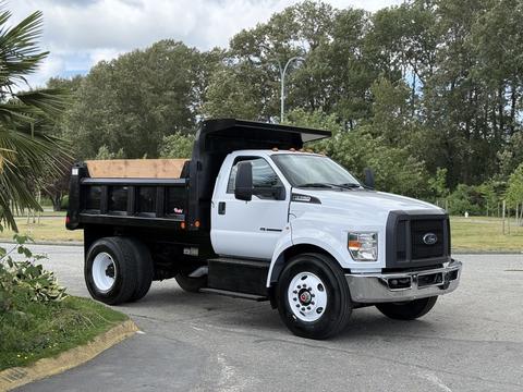 A 2017 Ford F-750 truck with a black dump bed, featuring a white cab and large wheels parked on a roadway