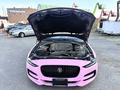 A 2020 Jaguar XE with its hood raised displaying the engine compartment painted in pink with various mechanical components visible