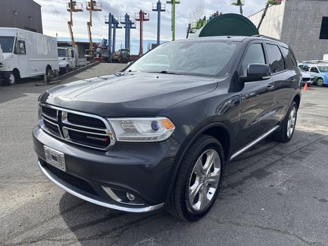A 2015 Dodge Durango in gray with chrome accents parked with a detailed view of its front headlights and grille
