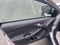 Interior view of a 2018 Ford Focus driver's side door with control buttons for windows and mirrors and a partially rolled down window showing raindrops on the glass