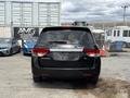 A 2014 Honda Odyssey minivan in black with a simple design featuring a chrome trim and the model name displayed on the rear hatch