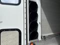 A 1994 GMC Vandura 3500 with a compartment featuring four circular black tubes arranged vertically