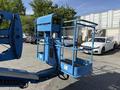 A blue Genie Z 45/25 aerial lift with an extended platform and safety rails is positioned in the foreground