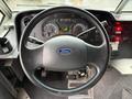 A black steering wheel with a blue Ford emblem in the center and various dashboard gauges and controls visible in the foreground