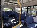 Interior view of a 2017 Chevrolet Express with blue upholstered seats arranged in rows and an empty space with a tire on the floor