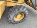 A large, worn tire from a 2012 John Deere 310SJ construction vehicle with a distinctive tread pattern and yellow rim