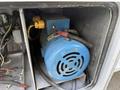 A blue electric motor with wires and connectors visible mounted inside a grey compartment