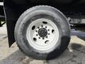A close-up of a large truck tire mounted on a wheel showing the tread pattern and metal rim with bolts