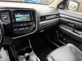 Interior of a 2016 Mitsubishi Outlander featuring a dashboard with a touchscreen display and control buttons along with a leather seat and gear shift