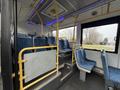 Interior of a 2016 Grande West Vicinity bus featuring blue patterned seats with yellow handrails and an elevated area with additional seating