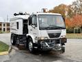 A 2009 UD Trucks UD 3300 street sweeper with a white body and a large front brush attachment for cleaning road surfaces