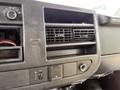 Close-up of the dashboard of a 2015 Chevrolet Express featuring air vents controls and a panel with buttons and an outlet