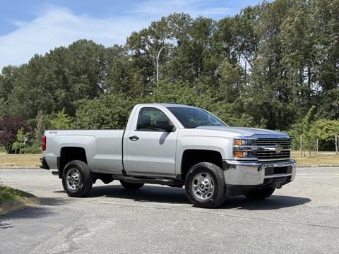 A 2016 Chevrolet Silverado 2500HD pickup truck in silver with a single cab and a long bed, parked with the driver side facing the viewer