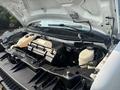 A 2021 Chevrolet Express with its hood raised revealing the engine compartment and various components including the coolant reservoir and battery