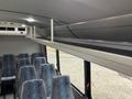 Interior view of a 2020 Chevrolet Express showcasing a row of grey seats with colorful pattern and an overhead luggage rack along the ceiling