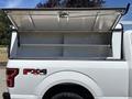 A white 2019 Ford F-150 with an open aluminum truck cap revealing empty storage space inside