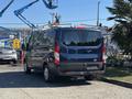 A 2016 Ford Transit 150 van with a roof rack parked in a lot showcasing its rear and side view