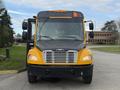 A 2022 Freightliner B2 yellow school bus with a black front, featuring a prominent grille and multiple windows, facing forward with its door open