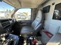 The interior of a 2013 Chevrolet Express showing the driver's seat and dashboard controls with a fire extinguisher nearby