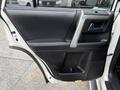 The interior door panel of a 2018 Toyota 4Runner featuring a black leather surface with a silver handle and window control buttons