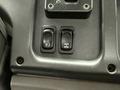 Two toggle switches on a dashboard console of a 2019 Freightliner M2 one with a circular icon and one with a gear shift pattern