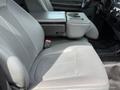 A gray driver's seat of a 2013 Ford F-550 with a center console featuring cup holders and armrest