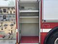 A 1999 Freightliner FL80 fire truck compartment with an empty metal shelf and a textured red floor mat