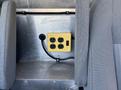 A yellow power outlet box with four electrical sockets and a power switch mounted on a metal panel between two gray seats
