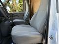 Interior of a 2024 Chevrolet Express showing two gray upholstered front seats and a center console with cup holders