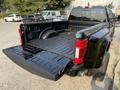 A black 2021 Ford F-350 SD pickup truck with an open bed revealing the truck's cargo area and tailgate in the lowered position