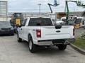 A 2018 Ford F-150 in white with a rear view showcasing its tailgate and bed with the 4x4 emblem prominently displayed