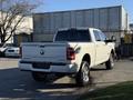 A white 2023 RAM 3500 pickup truck with a spacious crew cab and chrome wheels is parked, showcasing its robust design and rear profile