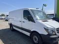 A 2016 Mercedes-Benz Sprinter van with a white exterior and black accents parked with a large front windshield and sliding side door