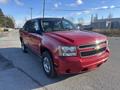 A red 2011 Chevrolet Avalanche with black trim and chrome accents parked on a road featuring a distinctive truck design with a spacious cabin and bed