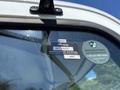 A close-up of the windshield of a 2020 Hino 338 displaying various stickers including a certificate of approval and roadside assistance information