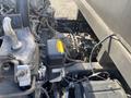 A close-up view of the engine compartment of a 2019 Hino 195 showing various components including pipes, wires, and a black part with an orange label