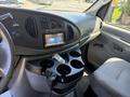 Interior of a 2006 Ford Econoline featuring a dashboard with a central display screen and several cup holders in the console