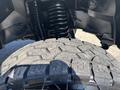 A 2018 RAM 3500 truck's tire with an aggressive tread pattern and a close-up view of the suspension assembly above it