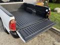 A 2013 Toyota Tacoma with an open tailgate revealing a black bed liner and no cargo inside