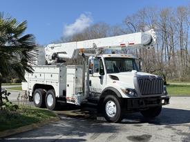 A white 2008 International 7500 truck with an elevated aerial work platform and tool storage compartments on the sides