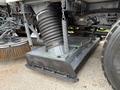 A close-up view of the underside of a 2009 UD Trucks UD 3300 showing a large circular vacuum system and a sweeping attachment with metal chains and springs