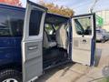 A blue 2013 Ford E-350 Super Duty van with open side doors revealing gray cloth seats and a spacious interior