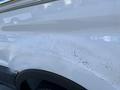 Close-up of the side of a 2017 Ford Transit with visible scratches and wear on the white paint surface