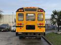 A yellow 2013 International 4300 school bus viewed from the rear showing its distinctive school bus lights and markings