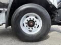 A close-up of a large truck tire mounted on a 2016 Freightliner 108SD showing raised tread and a white wheel rim with multiple lug nut openings