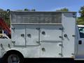 A white 2013 Ford F-550 truck with multiple storage compartments and a textured metallic utility box on top