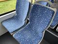 Two blue bus seats with a geometric pattern in pink and white set in a public transit vehicle